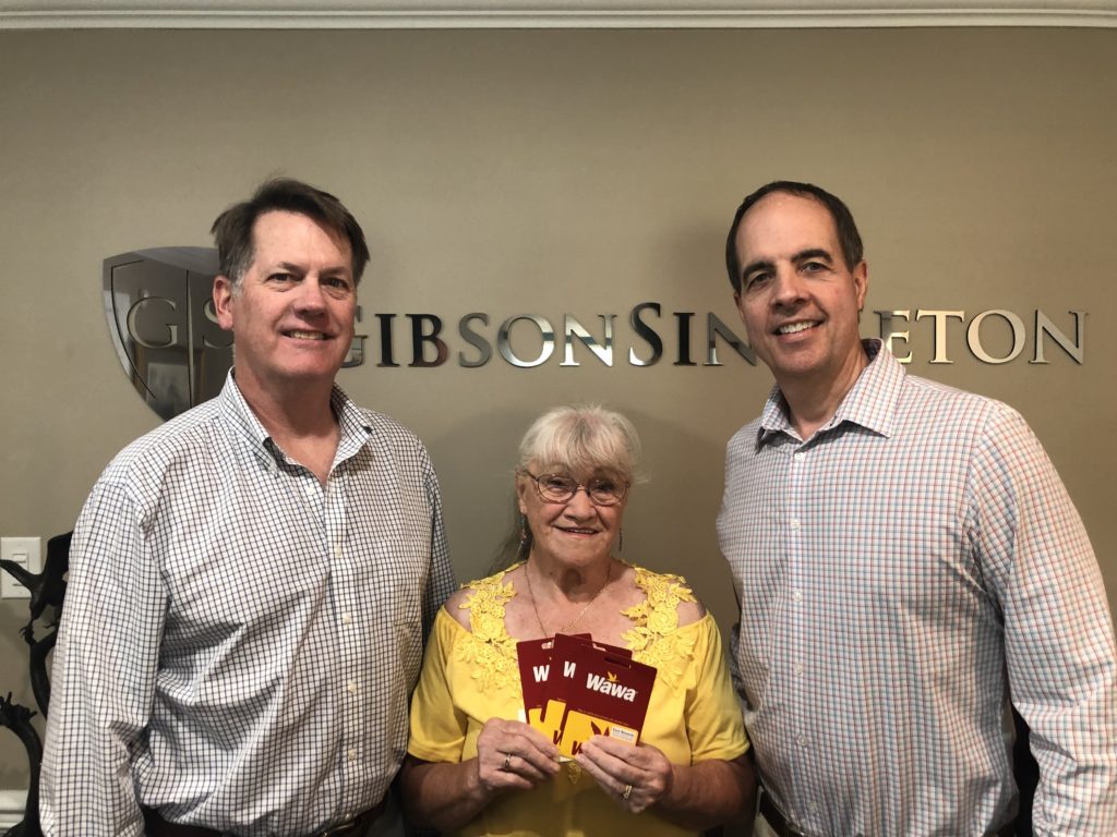 GibsonSingleton Virginia Injury Attorneys partners John Singleton and Ken Gibson present $300 in gas cards to Dutton resident Teresa Chandonnet of Dutton. Chandonnet is the winner of our firm’s drawing following our refrigerator magnet mailing to all Gloucester, Mathews, and Middlesex residents. The magnets contain non-emergency numbers for each county as a quick reference guide. Anyone not receiving a magnet may call us at (804) 413-6777 or come by the office to get one at 4073 George Washington Memorial Highway, Hayes.
