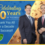 Ken Gibson and John Singleton on a banner that reads "Celebrating 10 Years. Thank you all for a decade of success."