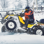 A man riding a ATV in the snow.