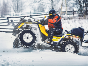 A man riding a ATV in the snow.