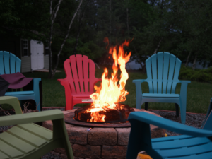 A firepit surrounded by summer chairs.