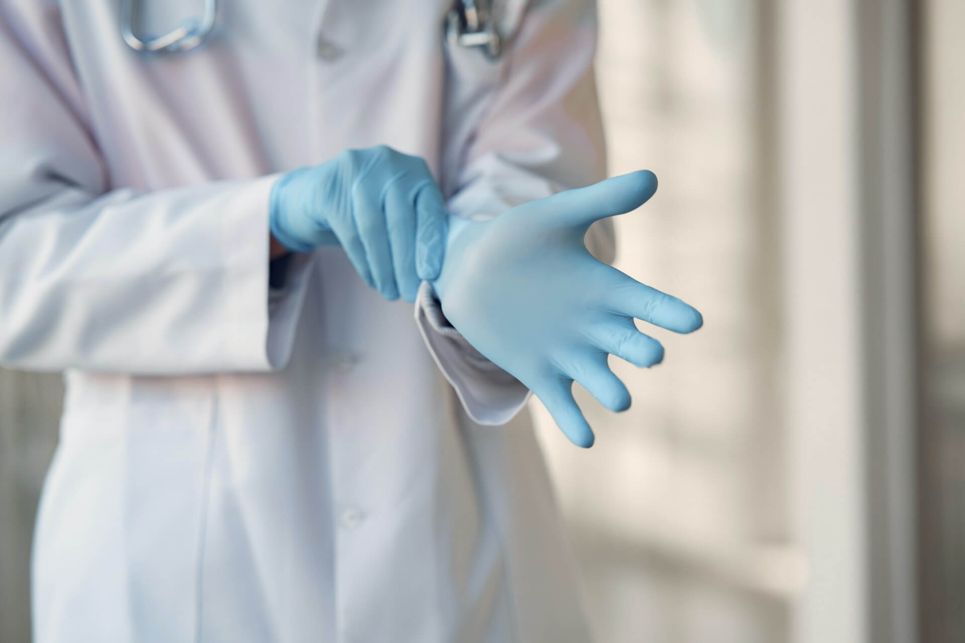Closeup of a doctor putting on blue gloves
