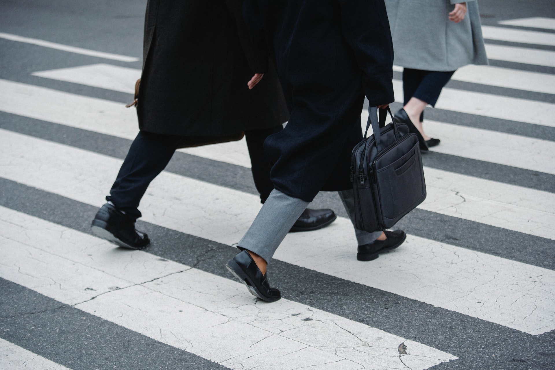 A shot of three people, shown from the waist down, who are crossing the street.