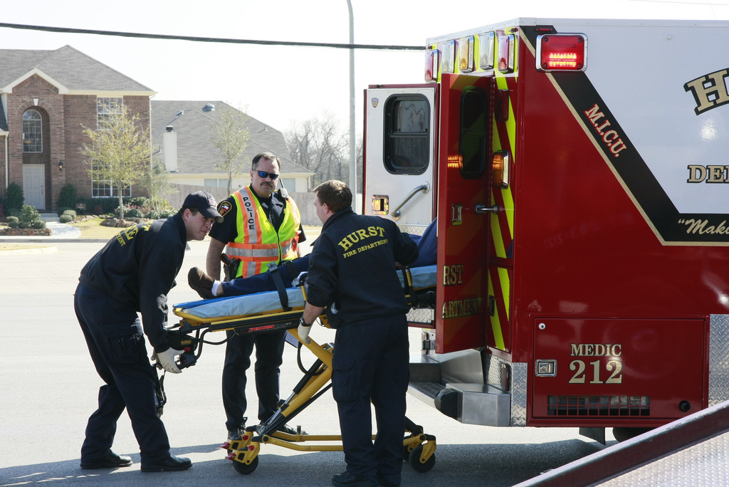 Person being loaded into an ambulance by several emts.